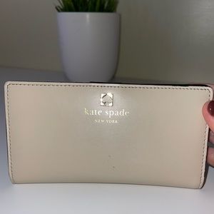 Cream Kate spade wallet with card holder slots.
